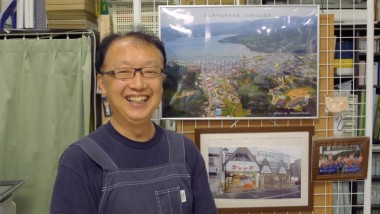 Mr. Kumagai, a local shop, keeping stands next to pictures of the town and his shop before the tsunami. 