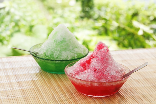 Two bowls of colorful kakigōri shaved ice with fruit syrup, a refreshing Japanese dessert enjoyed during summer.