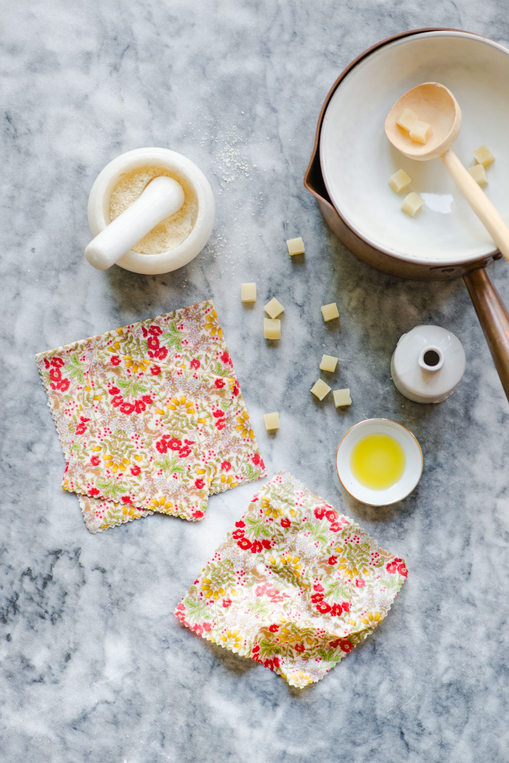 marble table with two colorful beeswax wraps, bowls and mortar