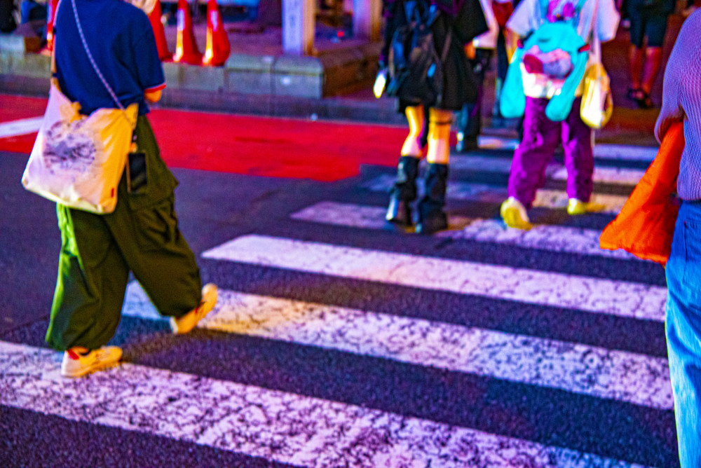 shot of people wearing colorful oversized clothing crossing a street