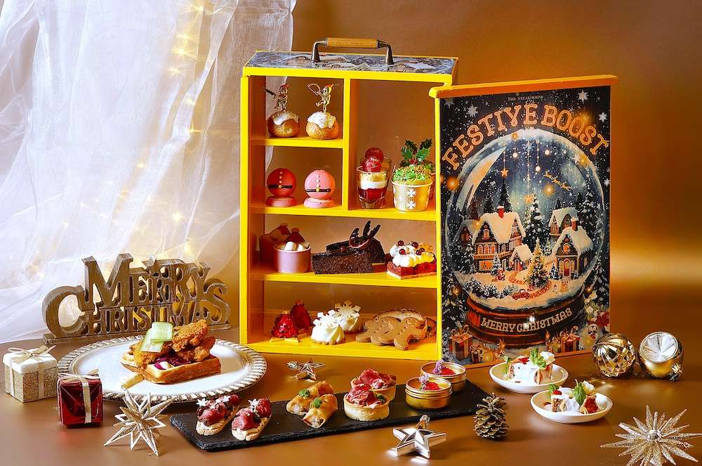 Two cups of tea, Christmas ornament-shaped and Santa hat-shaped desserts sit on a silver tray with other holiday decorations for the Maison Marunouchi Four Seasons Hotel Tokyo Afternoon Tea set.