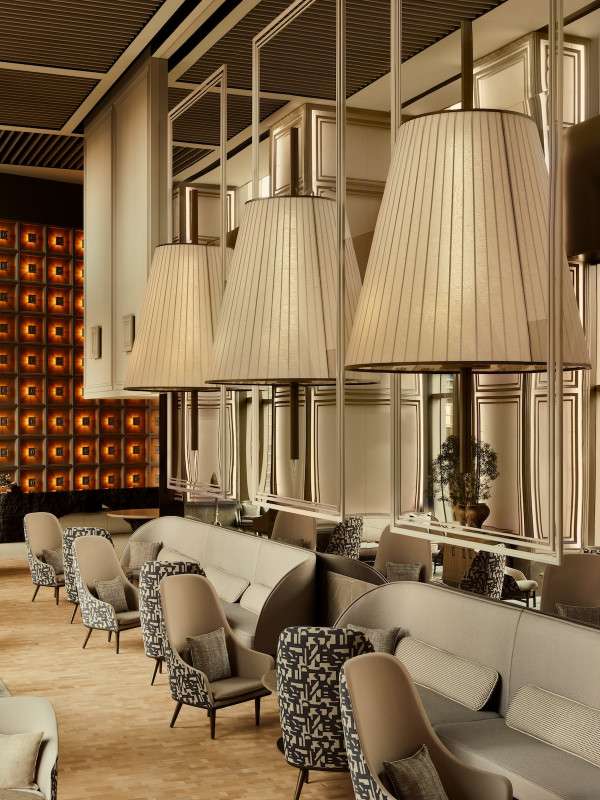 A photo showing the interior of Janu Tokyo's lounge, minimal and beige fabric around the couches with giant lamp shades above them.