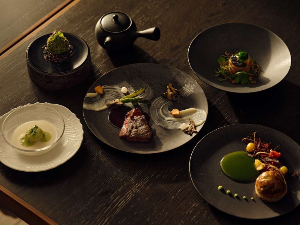 A photo of 6 dishes from above. Japanese bonsai-inspired haute cuisine dishes served at Janu Grill. Each dishes display zen and kaiseki-esque aesthetics. The dishes are displayed on dark wooden table.