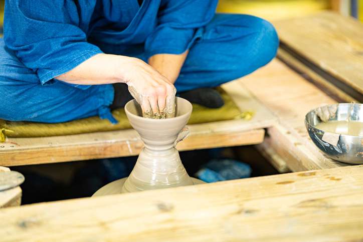 A potter shapes a ceramic vessel on a pottery wheel during a traditional Japanese pottery workshop.