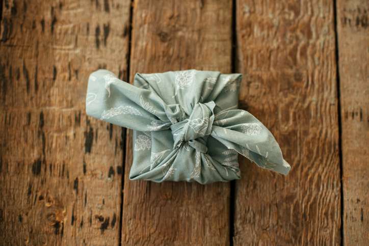 A small box wrapped using the traditional tying practices in blue fabric on a wooden table